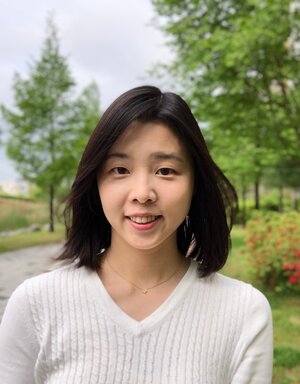 Headshot of Hwang in a white shirt against nature.