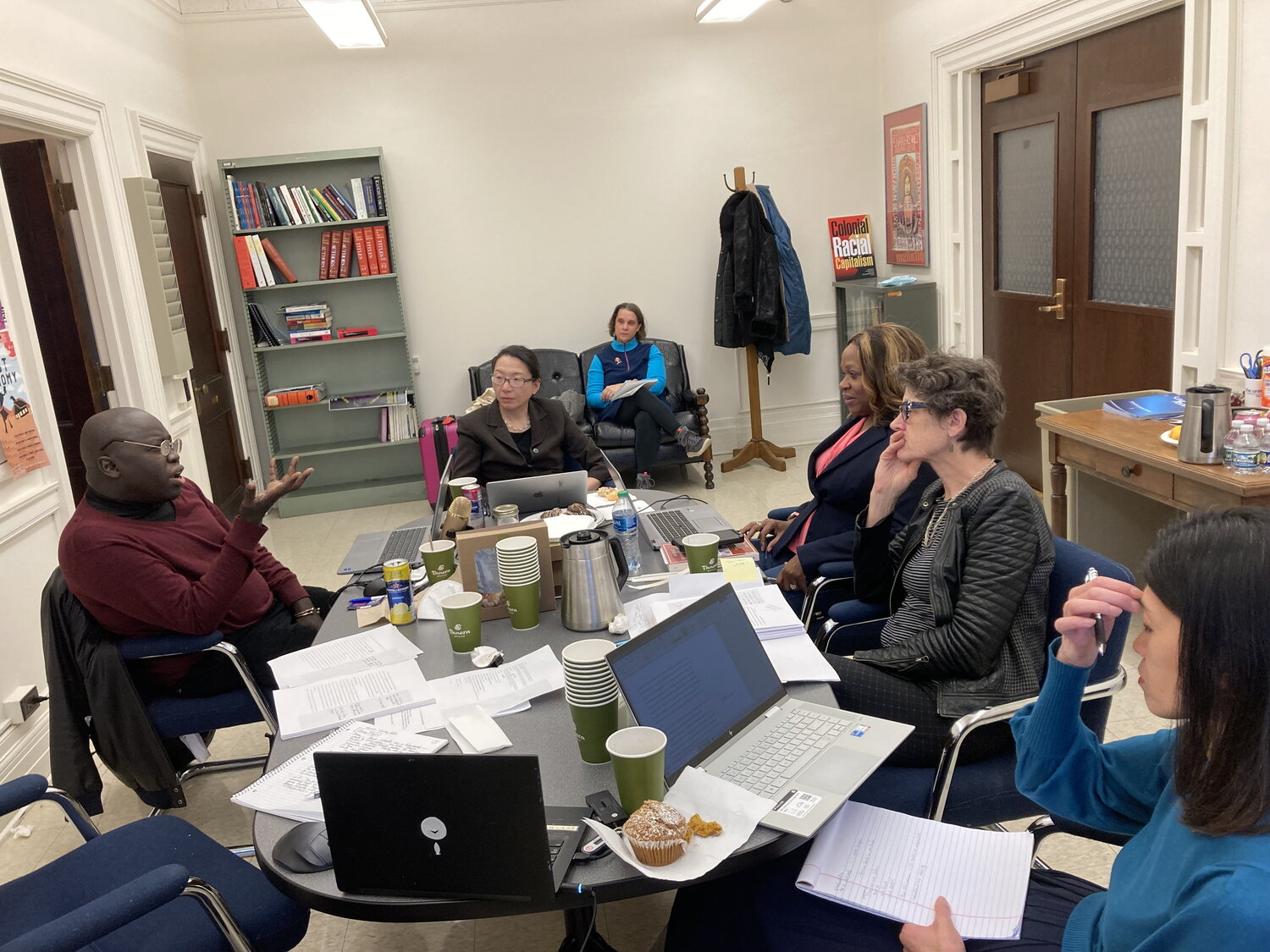 Professors sit around a table during a manuscript workshop.