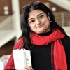 Nubras Samayeen stands in the landscape architecture building, wearing a red scarf and holding a white folder.