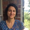 Grad Student Claire Baytaş stands outside against a brick wall and smiles at the camera.